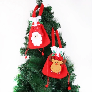 Detail of Christmas Santa and Reindeer non-woven gift bags hanging on a festive pine tree branch