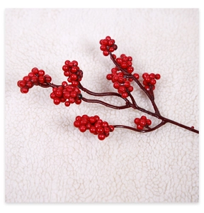 Macro detail of glossy red artificial berry stems on a soft white fur background