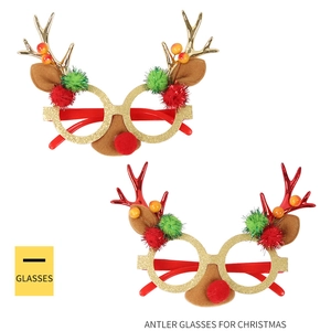 Close-up of Christmas antler glasses with red pom-pom nose and golden glitter finish