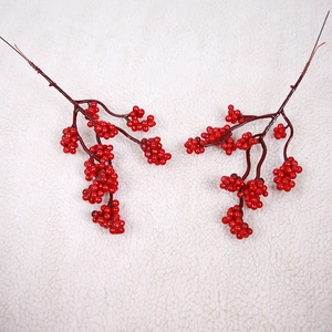 Close-up of artificial red berry branches for Christmas decor on white velvet fabric