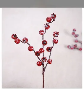 Close-up of artificial red berries branch with realistic snow texture for winter decor