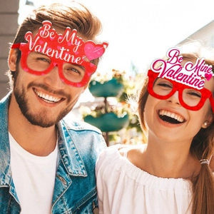 Red Valentine's Day party glasses with heart motifs and Be My Valentine text on a happy couple