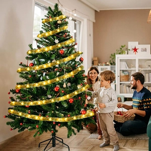 Christmas gold ribbon with warm LED lights glowing on a green tree for festive decor