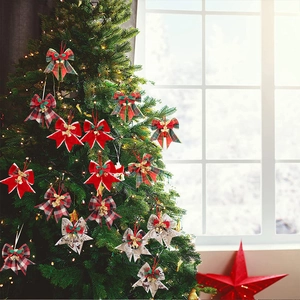 Detail of assorted Christmas bows with gold bells and pine cones on a festive tree branch