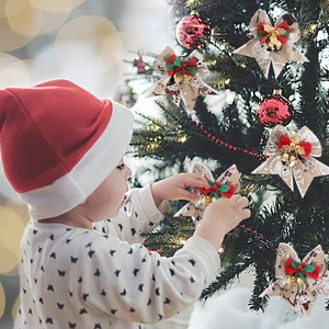 Close-up of rustic beige Christmas bow with snowman print and gold bells on a festive tree