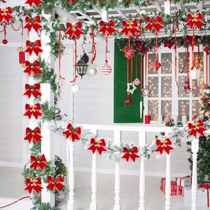 Red velvet Christmas bows with gold bells and pine needles on festive porch décor