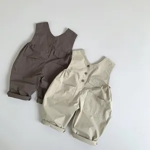 Detail of kids cotton overalls with multiple pockets and button-back design in earth tones