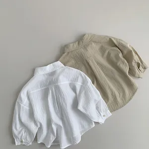 Flat lay of soft cotton linen kids shirts in white and khaki showing breathable fabric texture