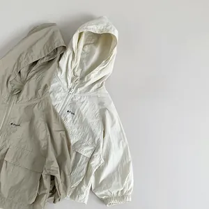 Detail of lightweight kids sun protection jackets with 'Plant.' logo in beige and cream