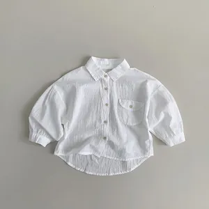 Detail view of white cotton linen kids shirt with chest pocket and curved hem line