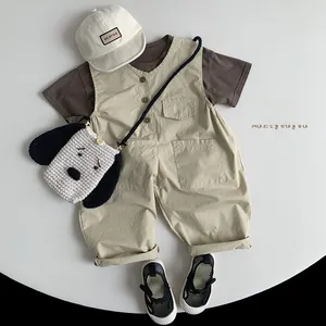 Flat lay of child summer outfit with brown cotton tee, khaki overalls, and a hat