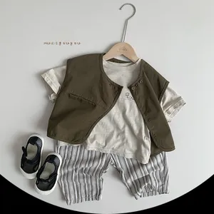 Flat lay of Korean style kids summer outfit with t-shirt, vest, striped shorts and shoes