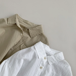 Detail view of khaki and white linen shirts showing fabric texture and button design