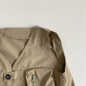 Detail of khaki utility vest showing V-neckline and 3D zipper pocket for kids