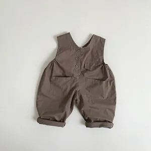 Detail view of brown vintage cotton baby overalls with large pockets and three dark buttons