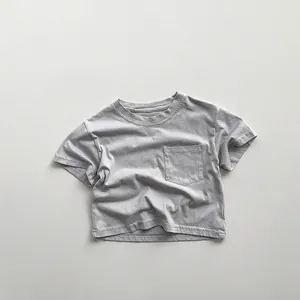 Detail shot of a minimalist grey cotton kids T-shirt featuring a small square chest pocket
