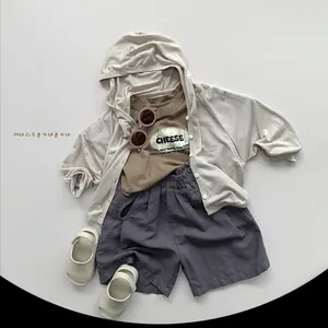 Detailed flat lay of children's cotton three-piece set including cardigan, t-shirt, and shorts