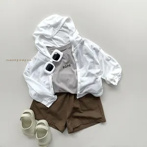 Flat lay of kids' summer sun protection set with white hoodie and casual brown shorts