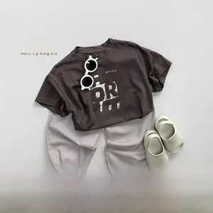 Detailed flat lay of children's summer outfit with grey t-shirt and purple mosquito pants