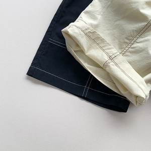 Detailansicht der Baumwollshorts mit Kontrastnähten und umgeschlagenem Saum in Schwarz und Beige