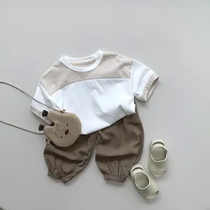 Flat lay of a children's summer outfit including a beige t-shirt and brown harem pants