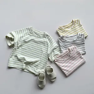 Vue à plat de quatre t-shirts à rayures pour enfants et sandales à velcro crème