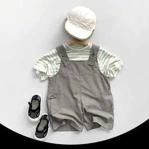 Completo estivo per bambini con maglietta a righe verdi e salopette grigia casual