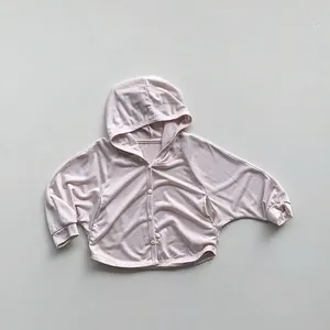 Detail view of pink hooded sun-protection cardigan with white buttons and ribbed cuffs