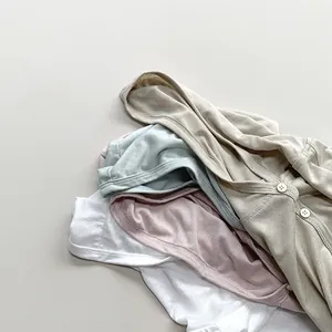 Close-up of baby cotton cardigans in beige, blue, pink and white showing button detail