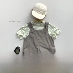 Détail d'un t-shirt à rayures vertes et blanches et d'une salopette cargo gris foncé