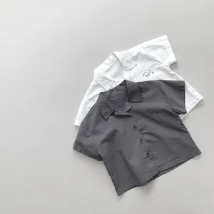 Detailed flat lay of lightweight cotton shirts in white and dark grey with cafe print