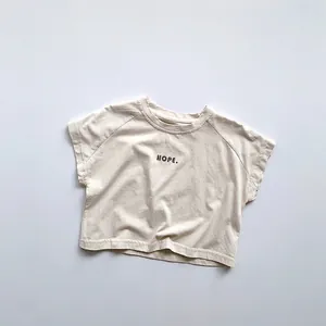 Détail de la texture en coton et de l'imprimé HOPE sur le t-shirt beige pour enfants