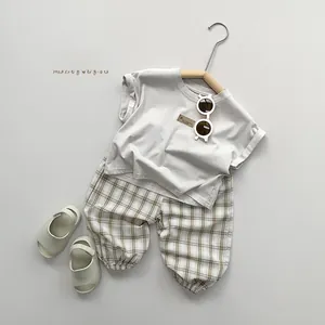 Mise à plat de t-shirt beige enfant et pantalon en lin à carreaux kaki de style scandinave