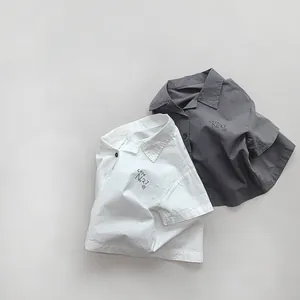 Flat lay of cotton kids shirts in white and dark grey with Cafe No.27 embroidery