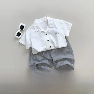 Flat lay of kids summer set with white cuban collar shirt and grey striped shorts