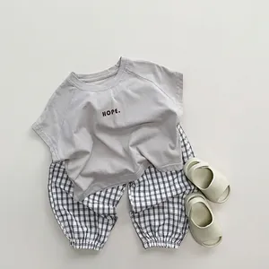 Kids summer casual set featuring a grey slogan T-shirt and black white plaid trousers