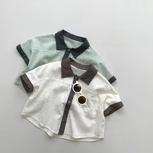 Flat lay of cotton linen kids short sleeve shirts with contrast collars in green and white