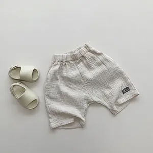 Detail of light beige double-layer cotton gauze kid shorts with elastic waist and letter patch