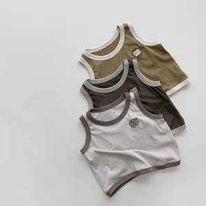 Détail de trois gilets sans manches pour enfants en maille olive, marron et gris doux