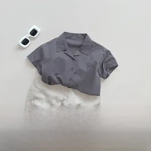 Flat lay of cotton kids summer set with grey short sleeve shirt and off-white shorts