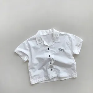 Detail of white cotton kids shirt with black buttons and cafe No.27 chest print