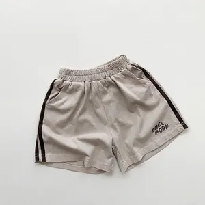 Détail du short en maille gris avec bandes latérales et texte imprimé pour enfant