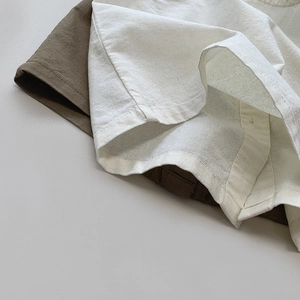 Close-up of linen blend fabric texture and double-stitched hem on a kid vest