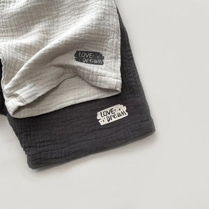 Detail of breathable double-layer cotton gauze shorts with decorative logo patches