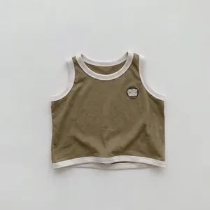 Détail macro du débardeur enfant vert olive avec bordures côtelées blanches et écusson