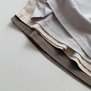 Détail de la double couture et du tissu en coton doux sur les ourlets du t-shirt