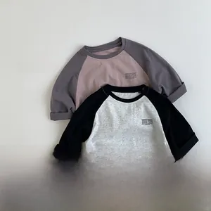 Detalle de camisetas raglán de manga larga para niños en tonos grises y púrpuras