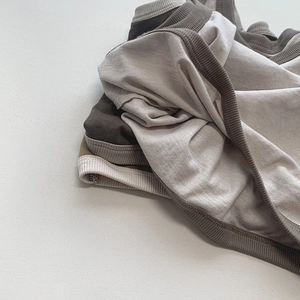 Détails de la texture en coton côtelé sur débardeurs pour enfants en beige et olive