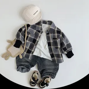 Flat lay of vintage gray washed denim jeans for kids with plaid shirt and casual accessories