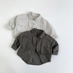 Flat lay of cotton kids' shirts showing workwear pockets and dual color fabric texture